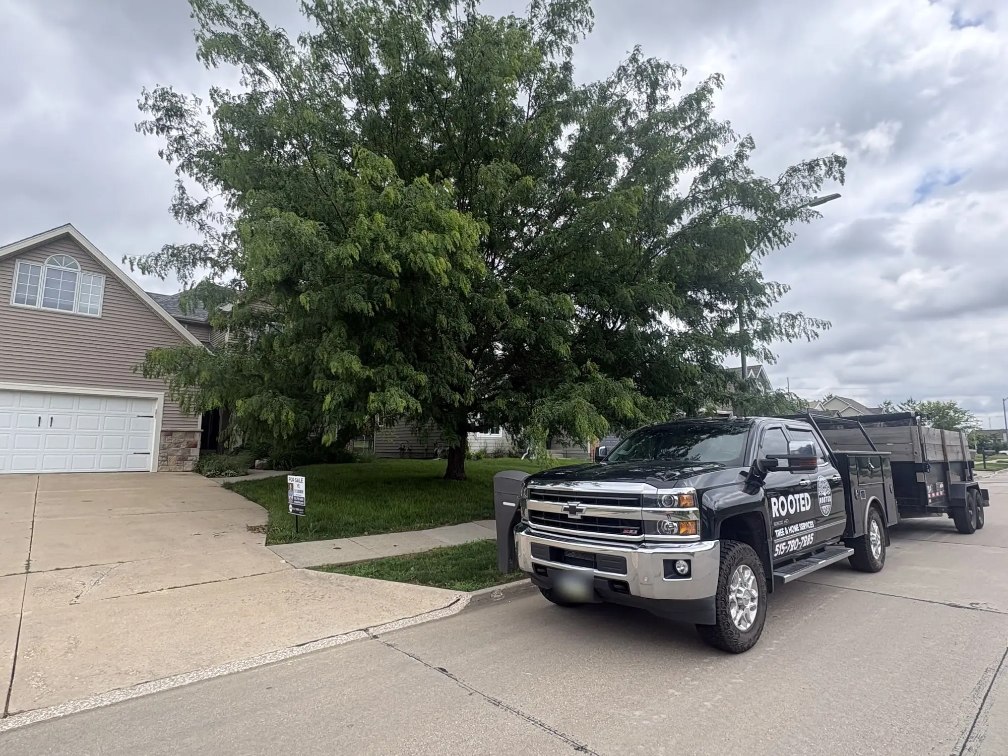Tyler's black Rooted truck and trailer parked outside a customer's house